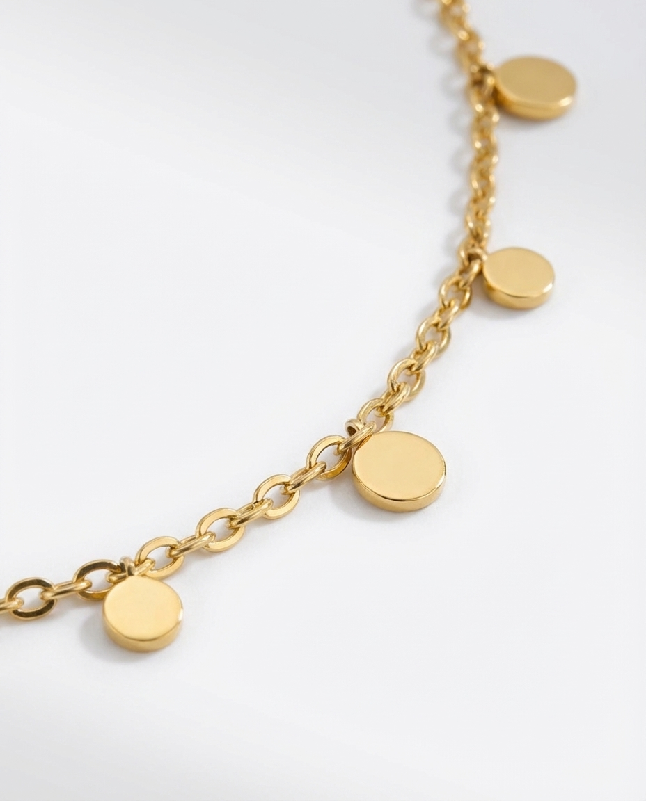 Macro detail of the gold disc charm necklace, showing the small round charms and craftsmanship of the chain.