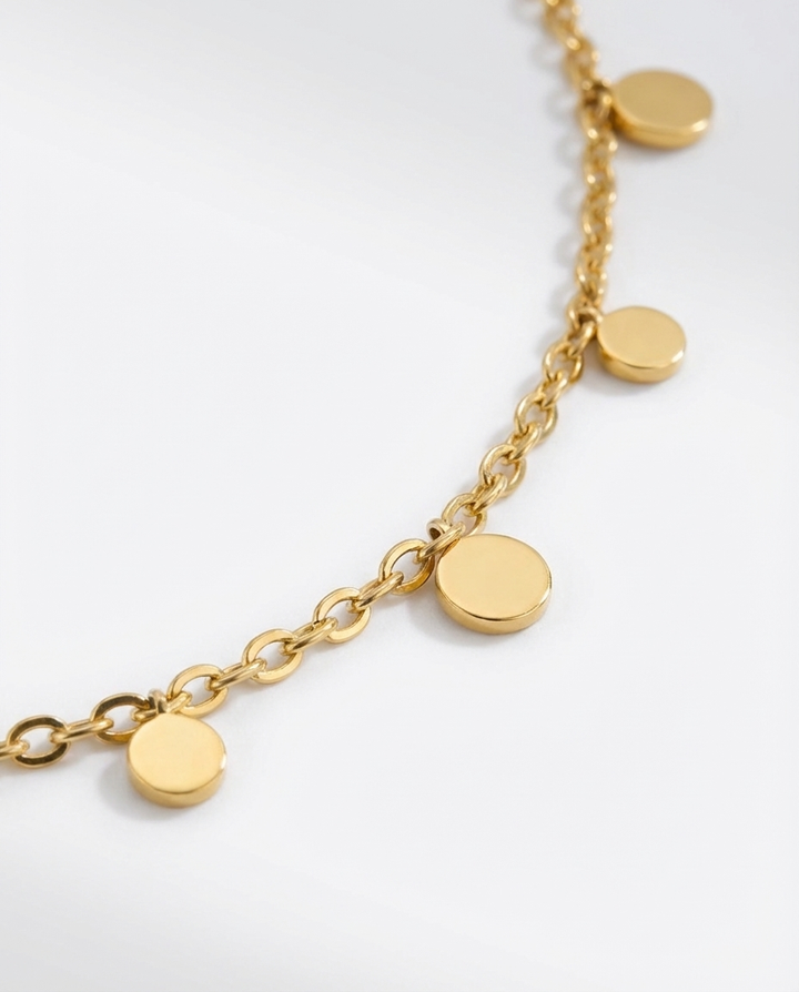 Macro detail of the gold disc charm necklace, showing the small round charms and craftsmanship of the chain.