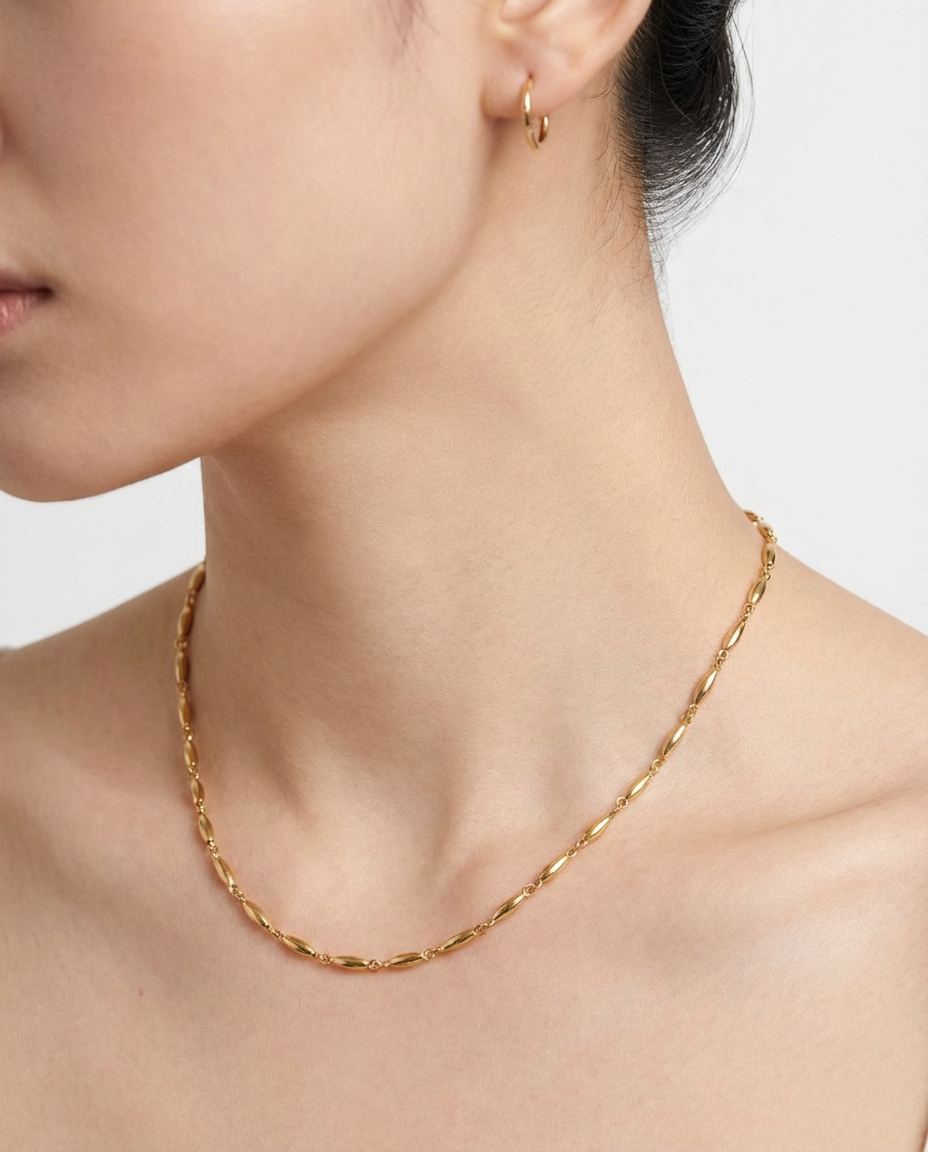 Close-up of the gold oval link chain necklace on the neckline, highlighting the polished oval links.