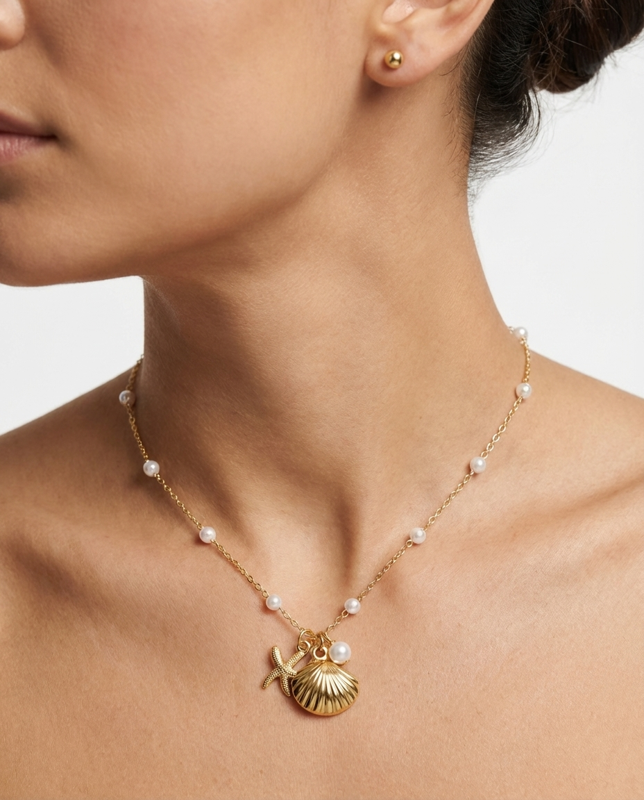 Close-up of the gold seashell and starfish pendant necklace on the neckline, showing the detailed pendant design.