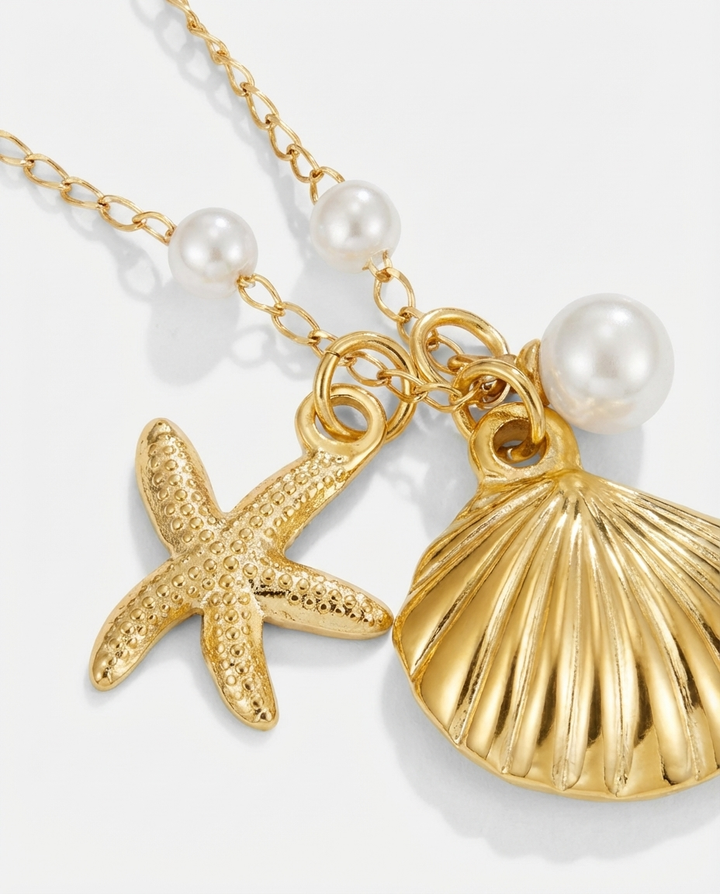 Macro detail of the gold seashell and starfish pendant necklace, showing texture, shine, and craftsmanship.