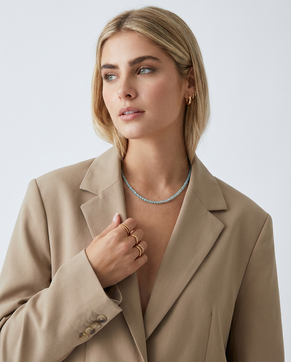 Woman wearing the light blue beaded necklace styled with a blazer, showing the soft pastel colour and refined look.