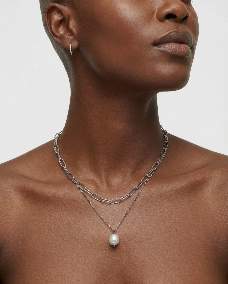 Close-up of the silver chain and pearl pendant necklace on the neckline, showing the refined and polished silver finish.