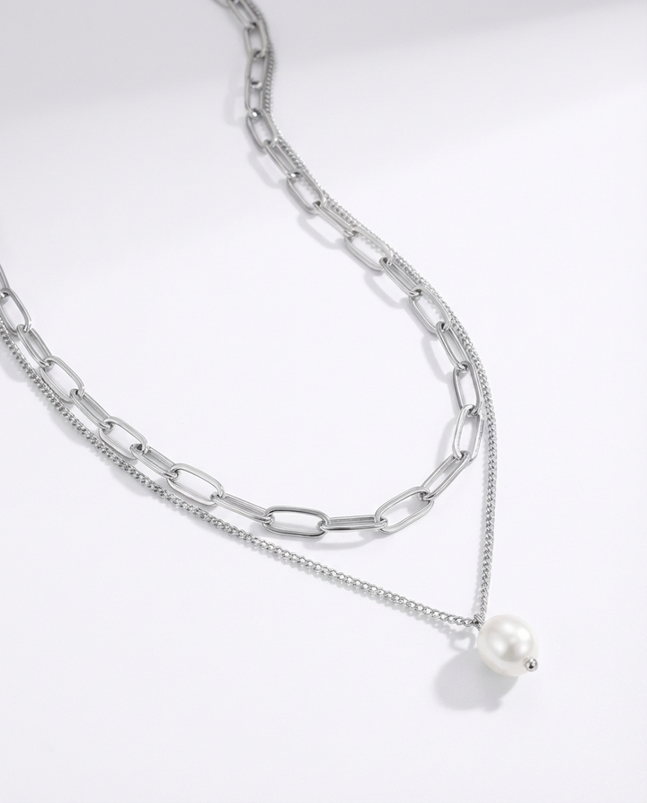 Macro detail of the silver chain and pearl pendant necklace, highlighting the texture of the chain and the smooth pearl detail.